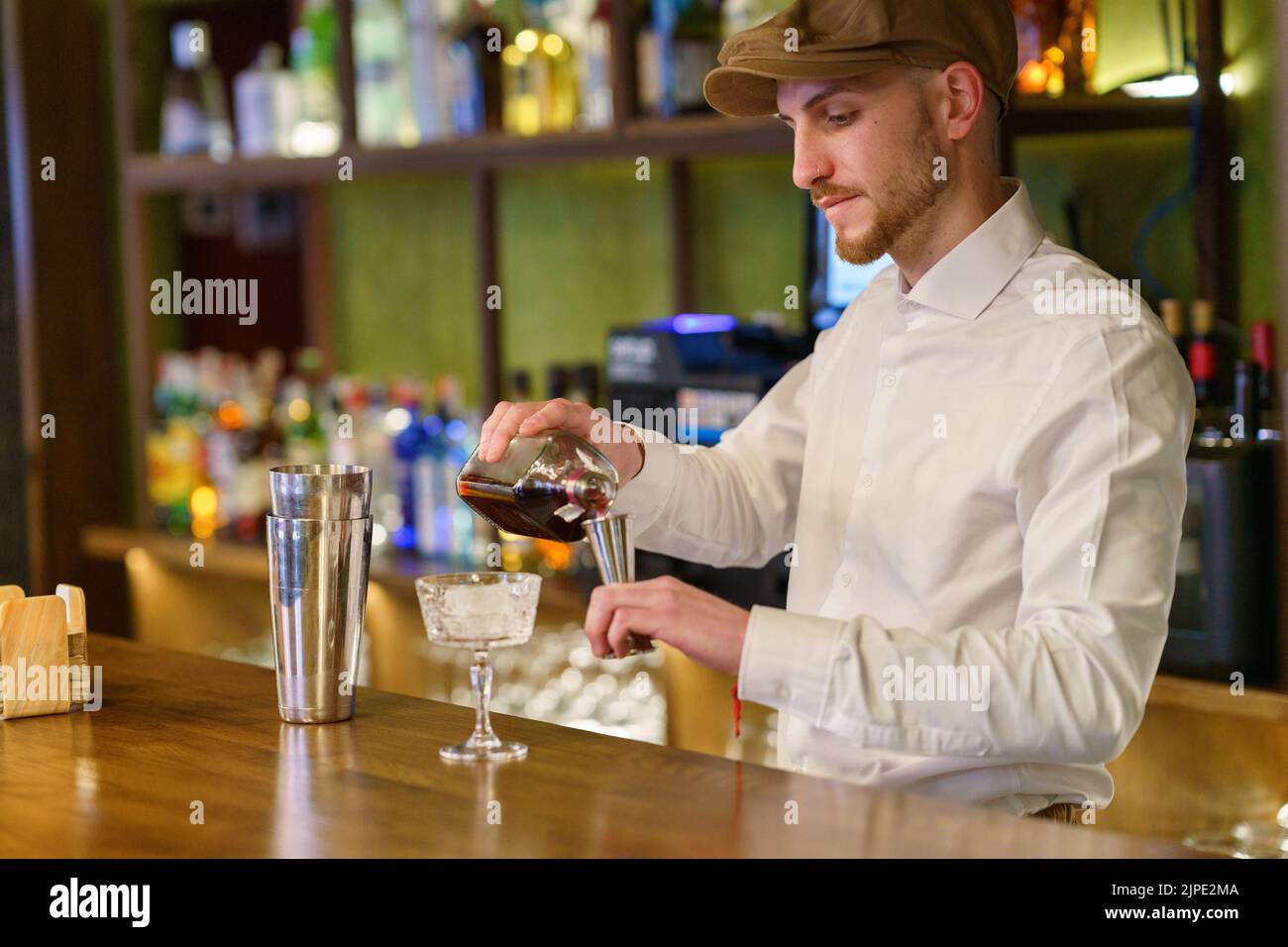 Male barkeeper pouring alcohol into shaker Stock Photo