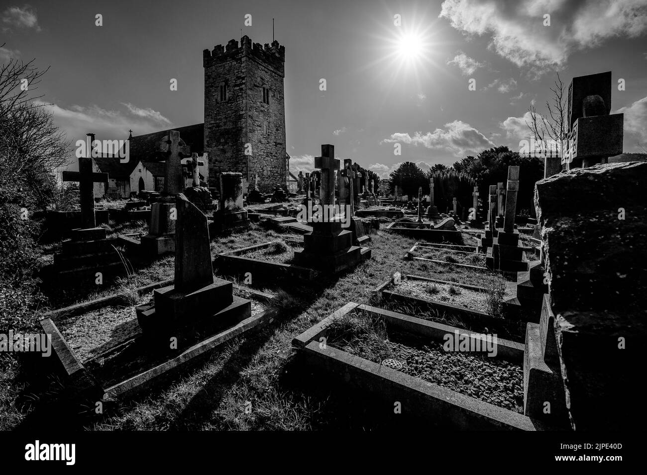 The sun shining over St Trillo's Parich Church and surrounding grave yard in Rhos on Sea, North Wales, UK. Stock Photo