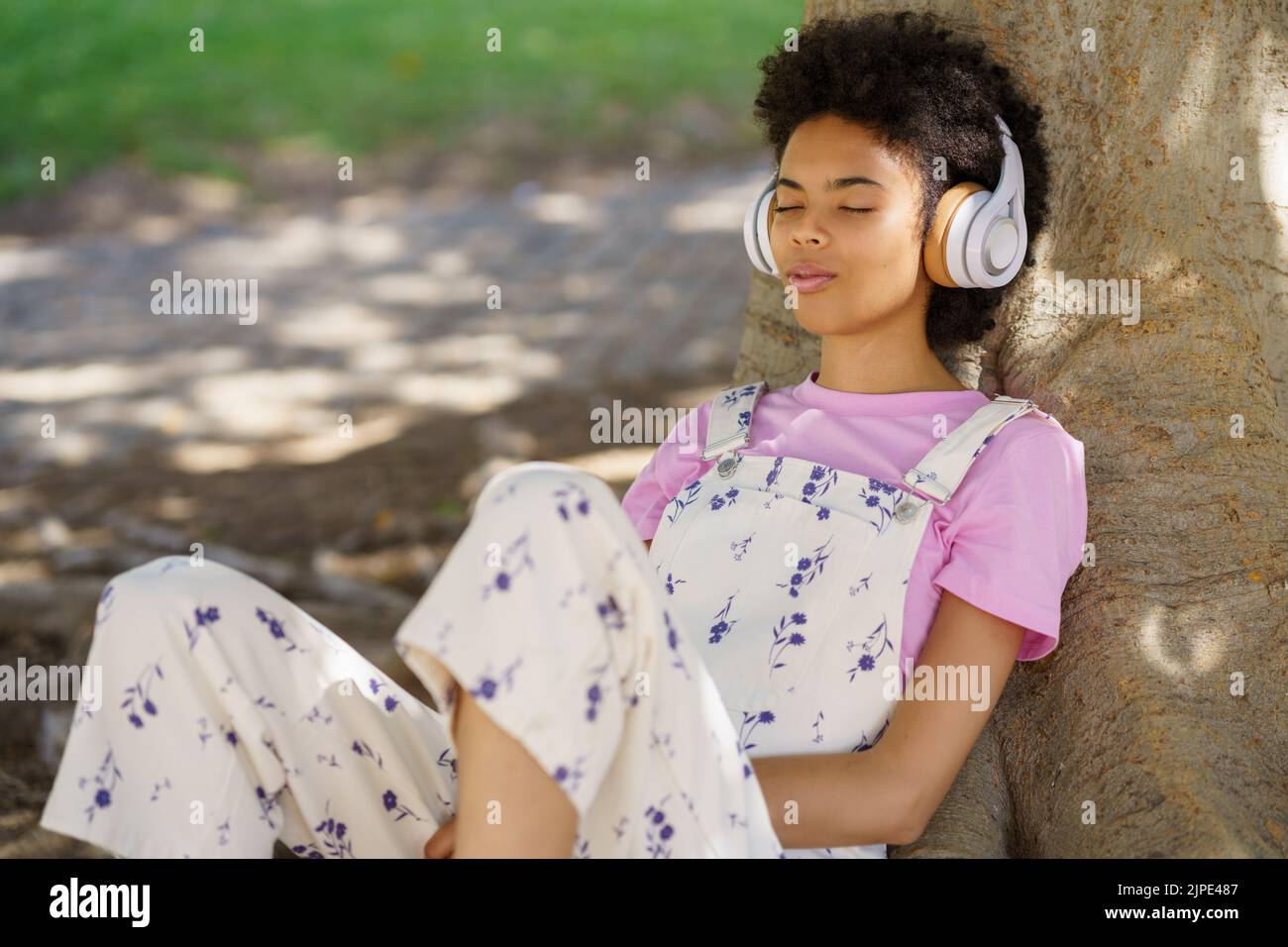 Black woman listening to song in park Stock Photo