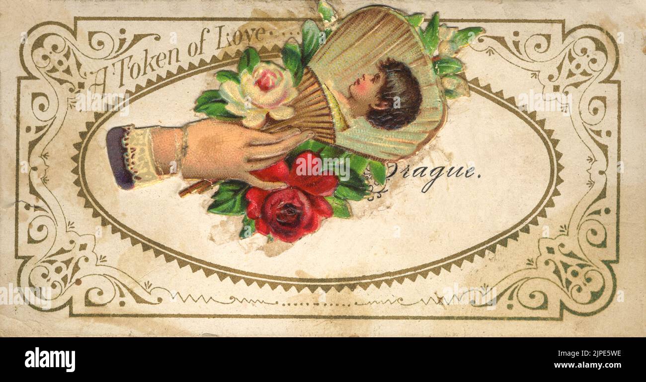 A TOKEN OF LOVE - Late 19th century or early 20th century Victorian vintage postcard with color illustration of hand holding roses and a paper fan with child portrait on it  - floral - circa 188s0 - 1900s Stock Photo