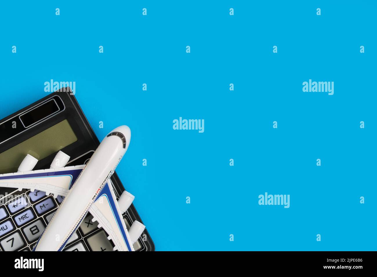 Airplane model and calculator blue background.Concept of costs or