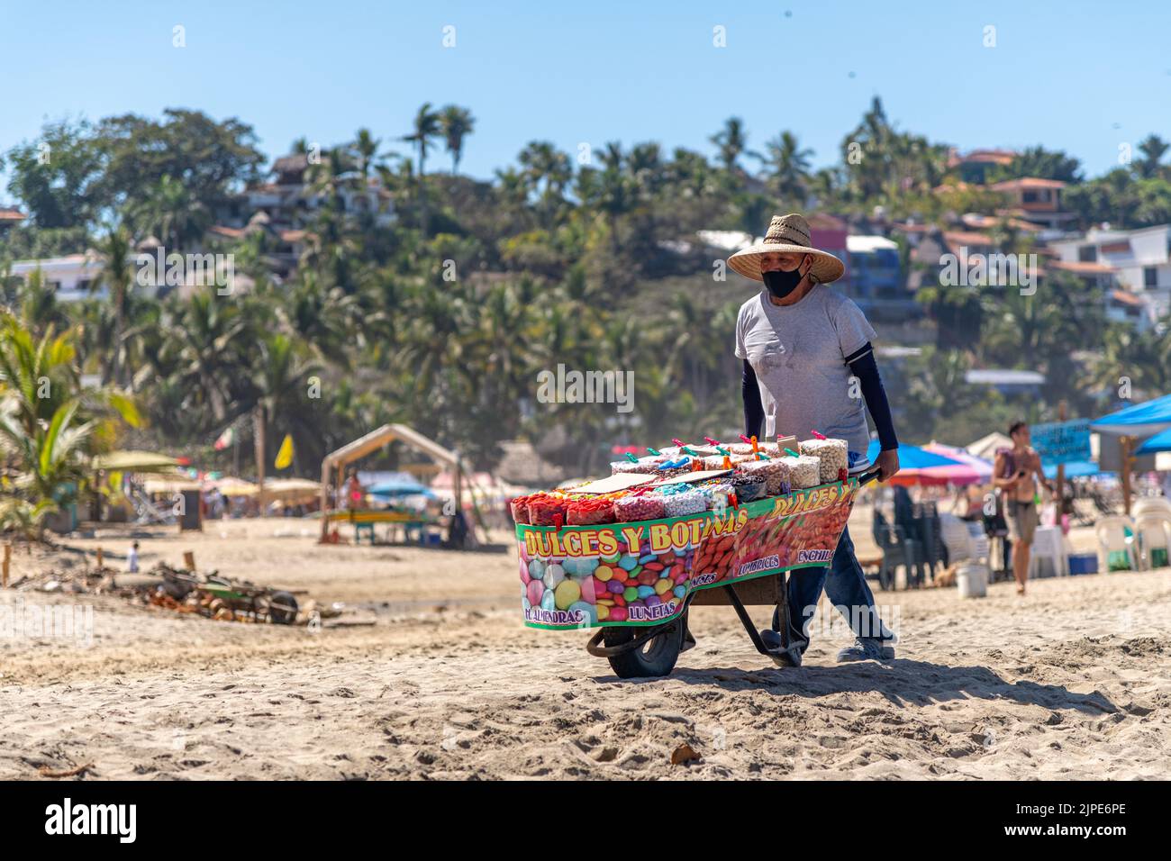 A man pushing a cart selling sweets and snacks on a beach in Sayulita, Mexico Stock Photo