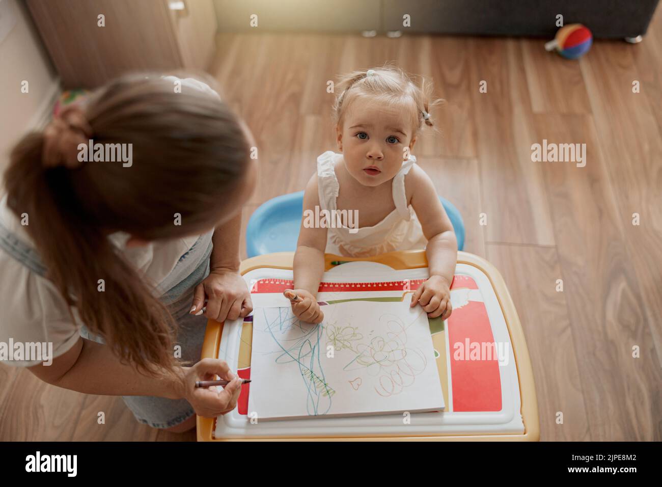 Little smiling girl painting with her mother at home while spending ...