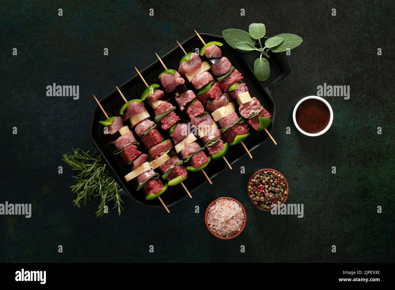 Raw meat skewers before cooking on a dark background. Stock Photo