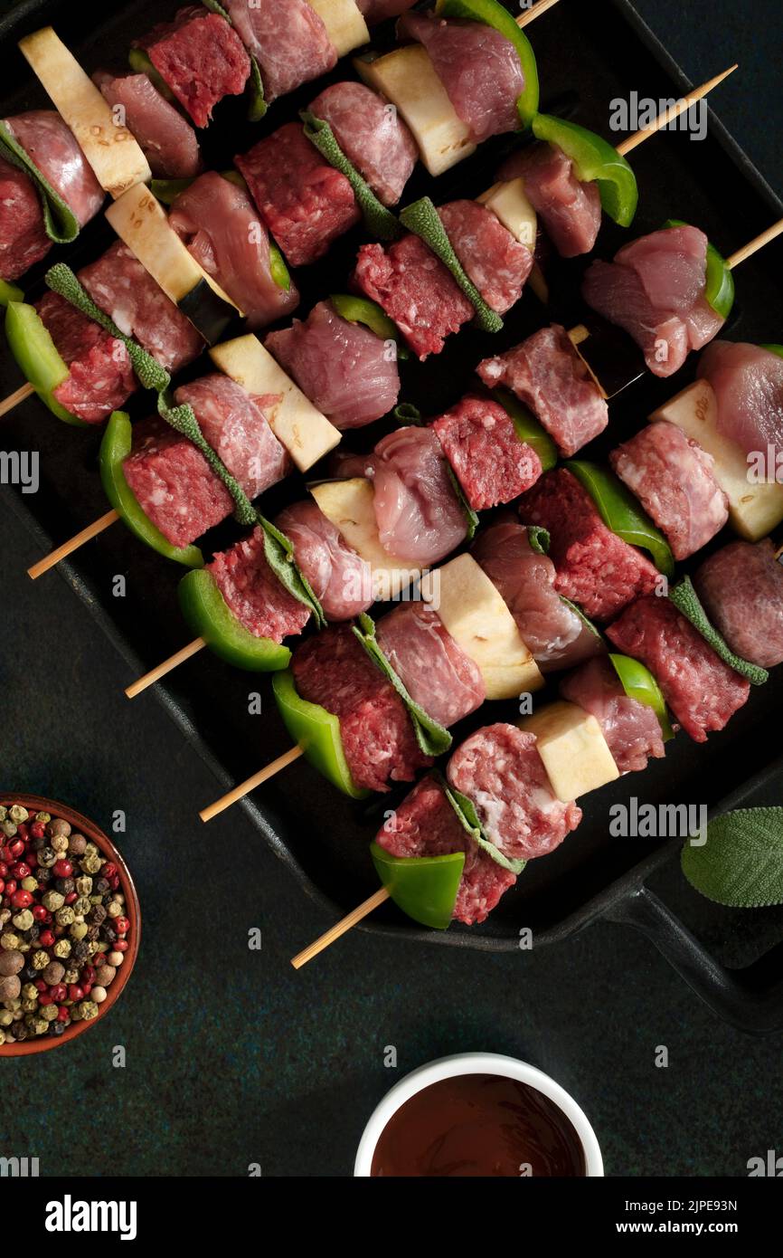 Raw meat skewers before cooking on a dark background. Stock Photo