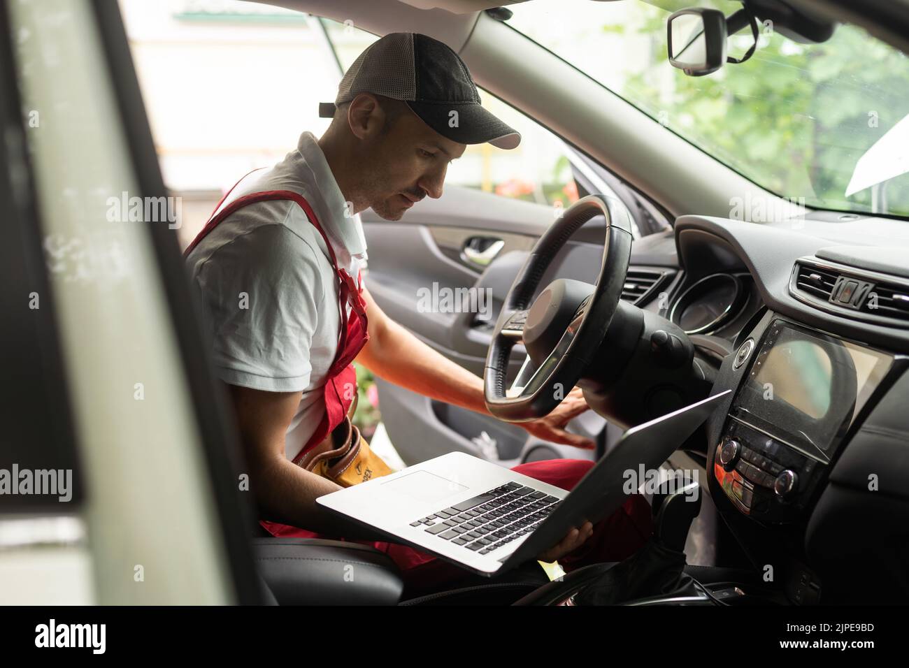 Mechanic with laptop near car engine. Modern car diagnostic program on