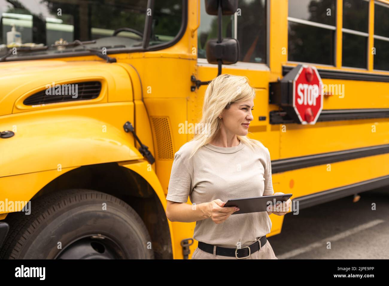 Portrait of cheerful teacher standing near the school bus Stock Photo ...