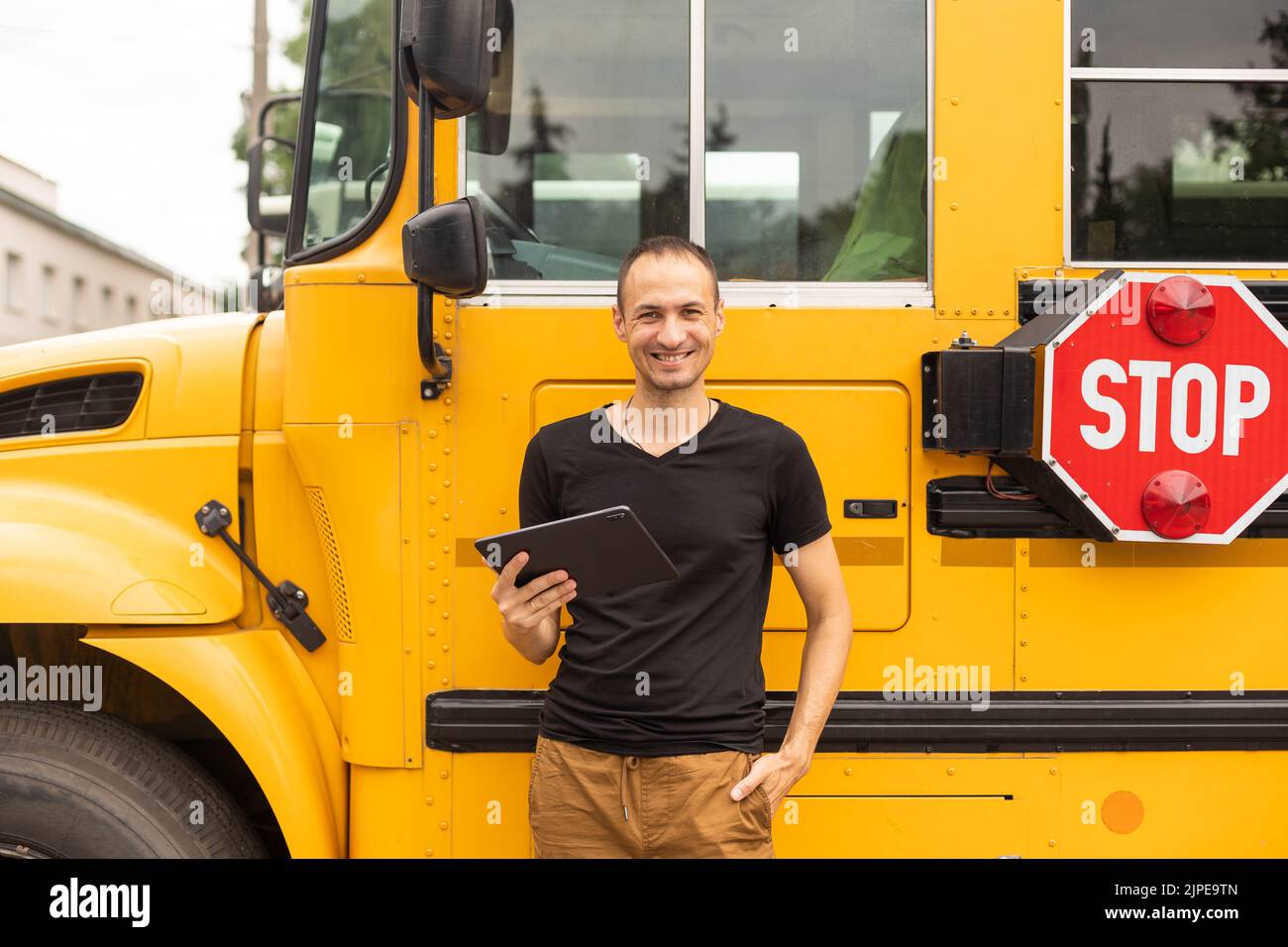 Portrait of teacher standing near the school bus Stock Photo - Alamy