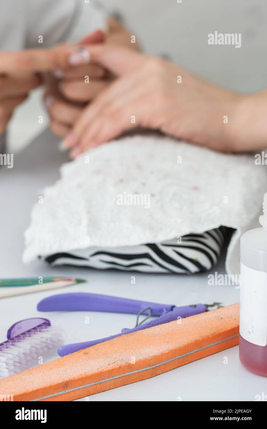 elements for the correct performance of a manicure, in the background a girl doing a nail cleaning. nail file, cuticle nipper and cuticle pusher. Stock Photo