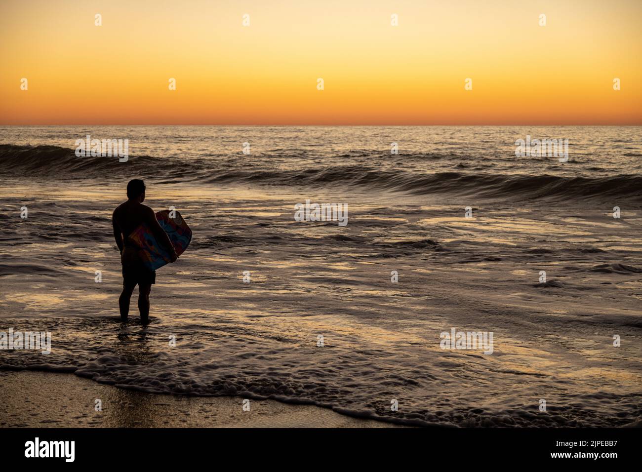 A surfer looking at a sunset on a beach in Sayulita, Mexico Stock Photo