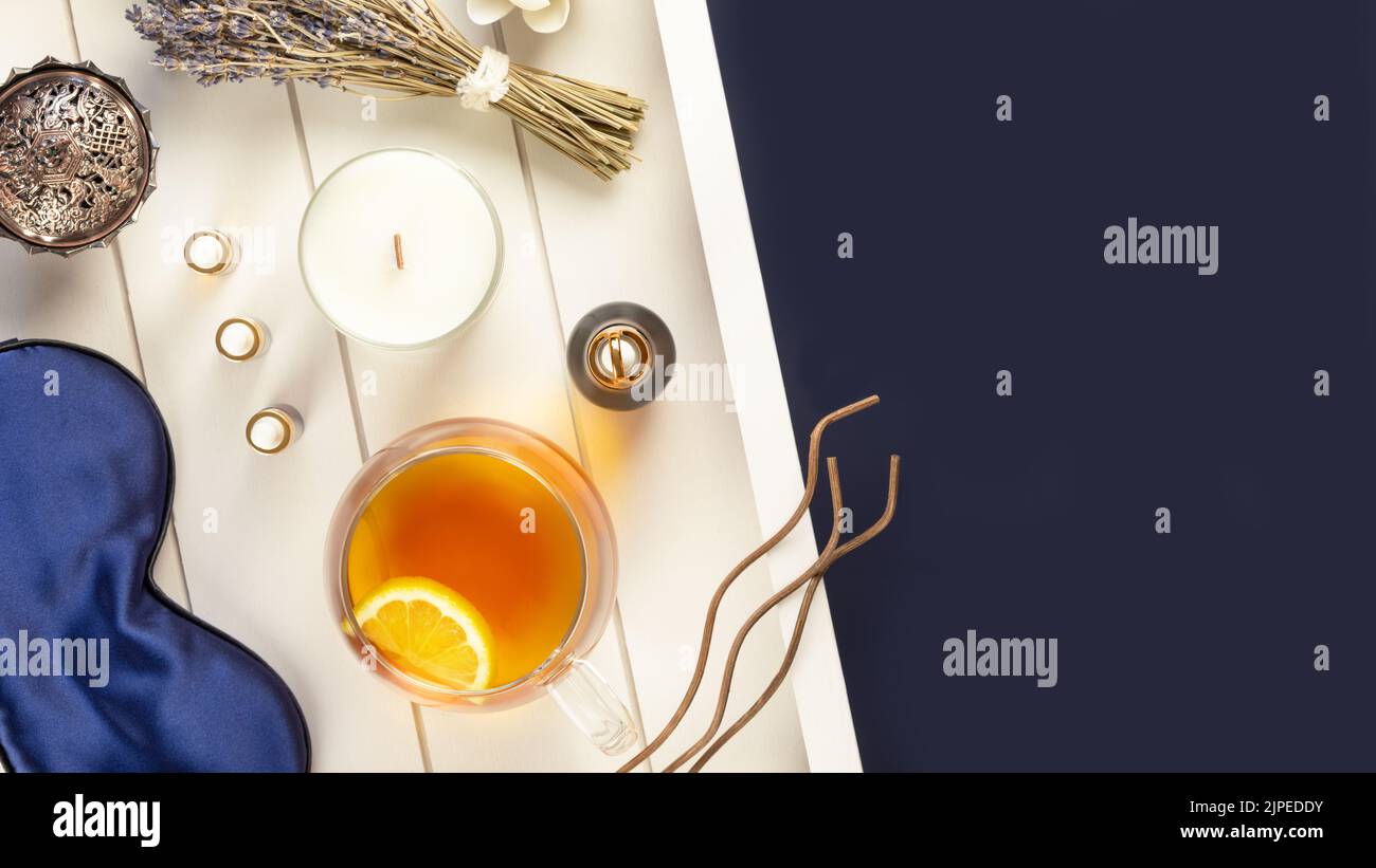 Self-care flat lay with blue sleeping mask, lavender flower, herbal tea, and natural oils on a white wooden tray with copy space. Concept of Me time a Stock Photo