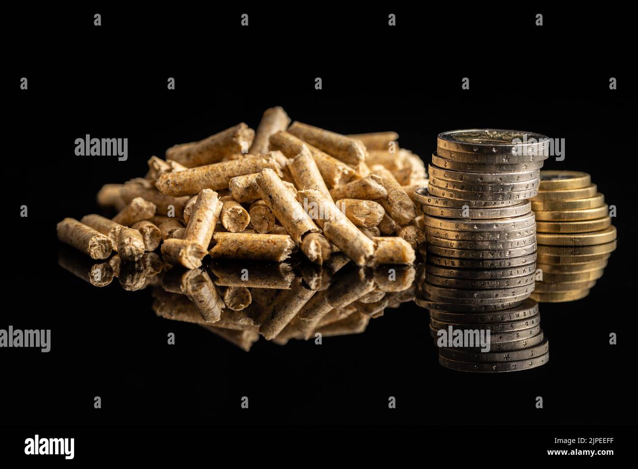 Wooden pellets and euro coins on black background. Biomass - Renewable source of heating. Stock Photo