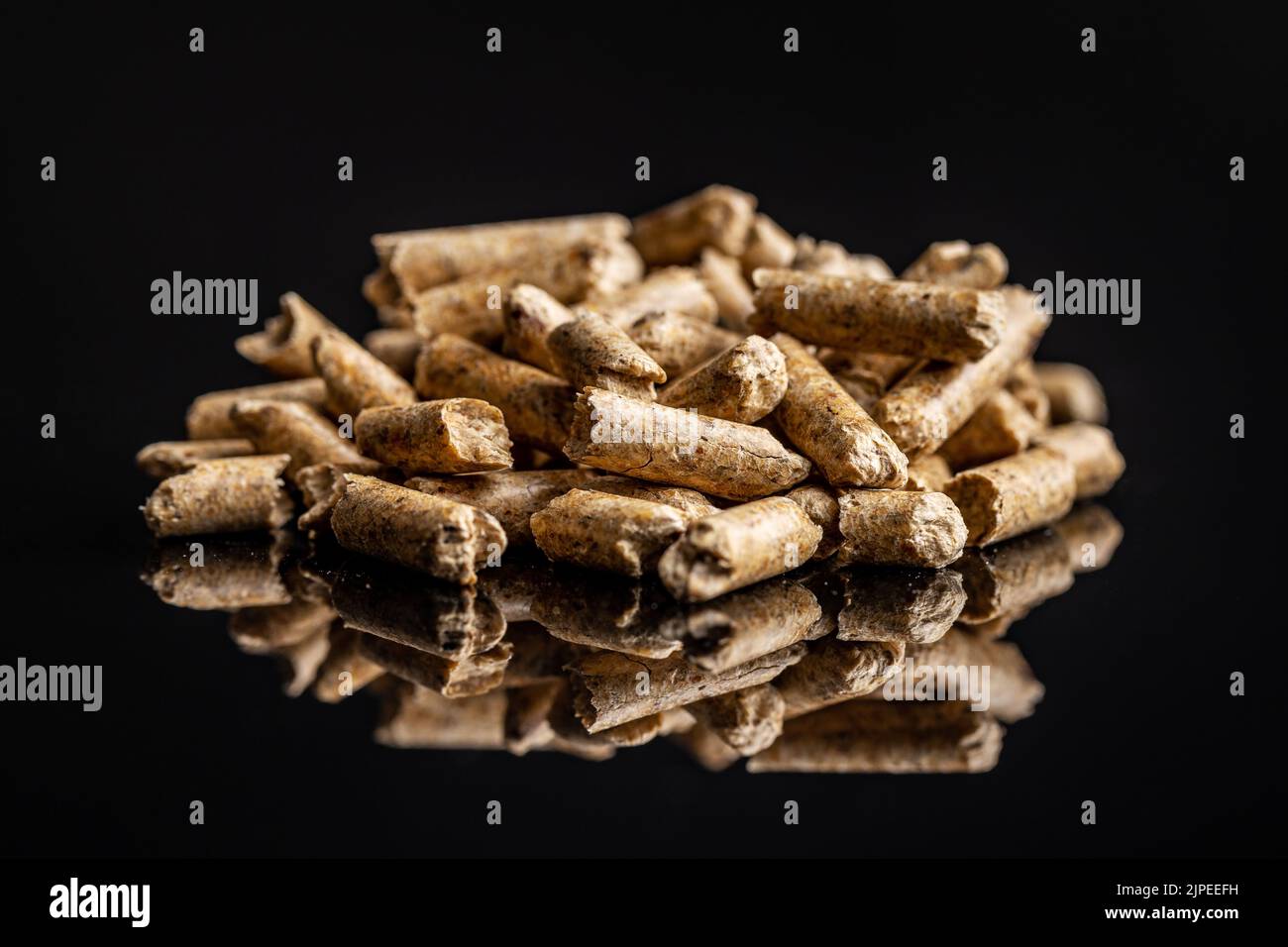 Wooden pellets on a black background. Biomass - Renewable source of heating. Stock Photo