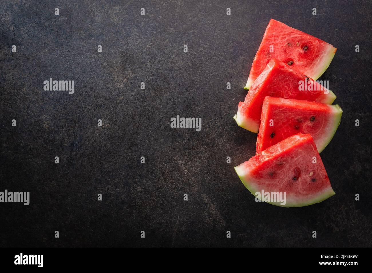 Slices of red watermelon on a black table. Top view. Stock Photo