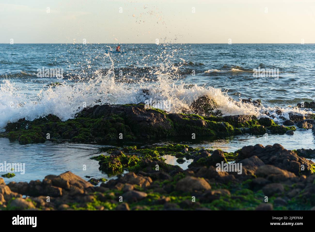 Salvador, Bahia, Brazil - December 11, 2021: Beach waves crashing on smooth and slippery rocks. Rio Vermelho beach in Salvador, Brazil. Stock Photo