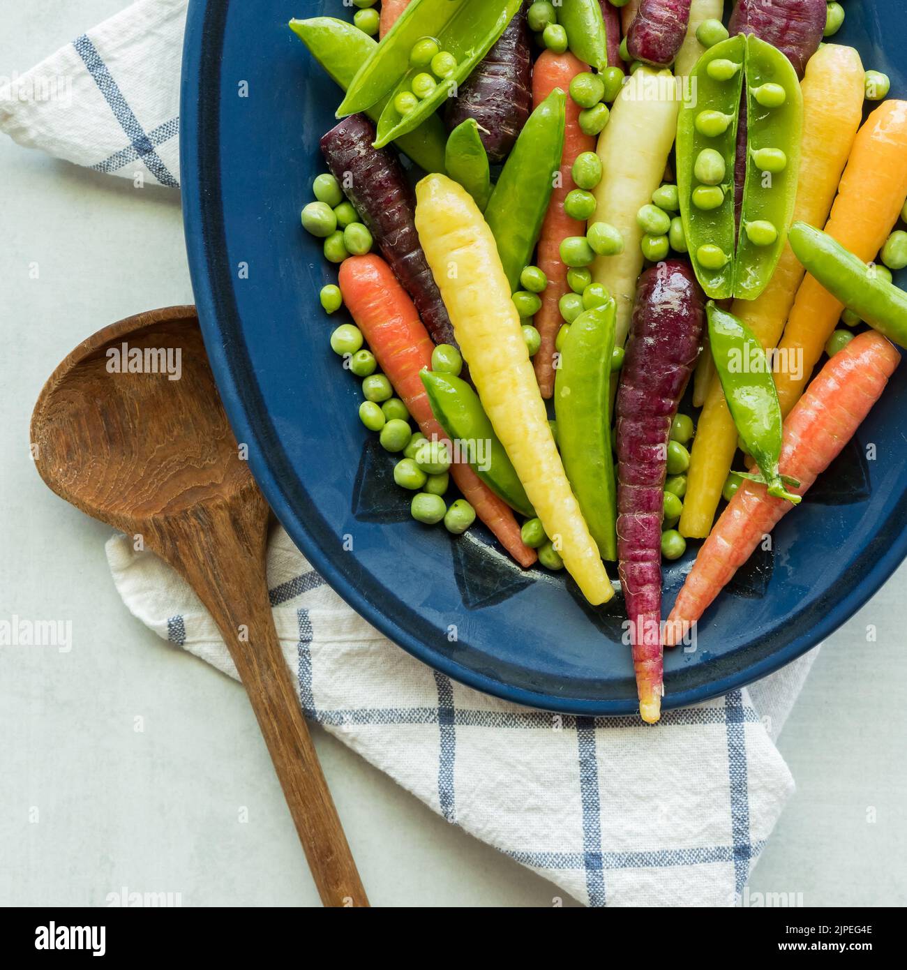 Close up view of a dish of rainbow baby carrots, peas and pea pods