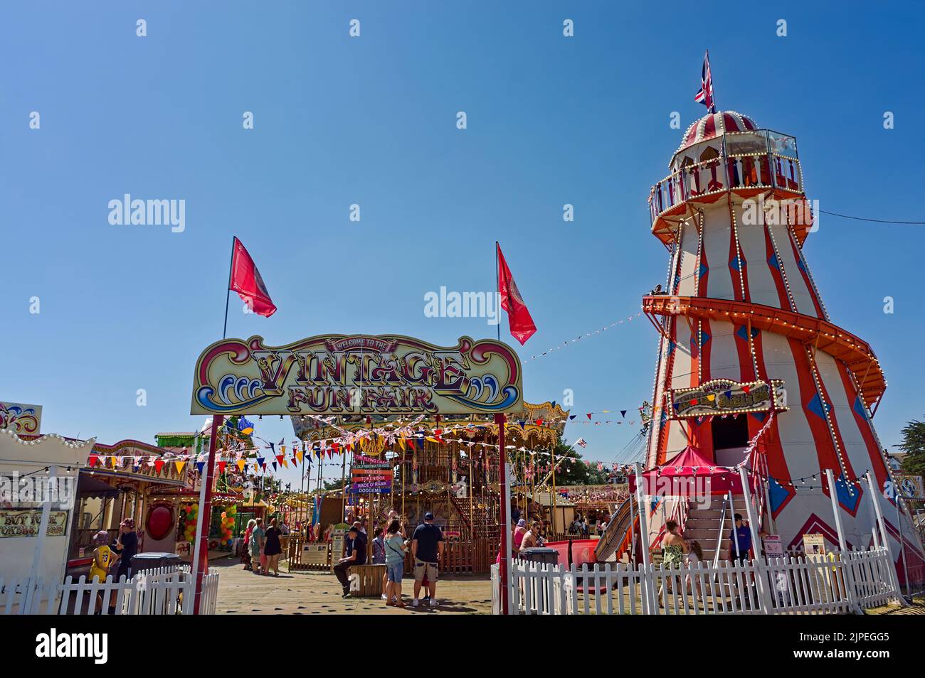 Vintage fun fair entrance with people enjoying the fairground on a hot sunny day Stock Photo