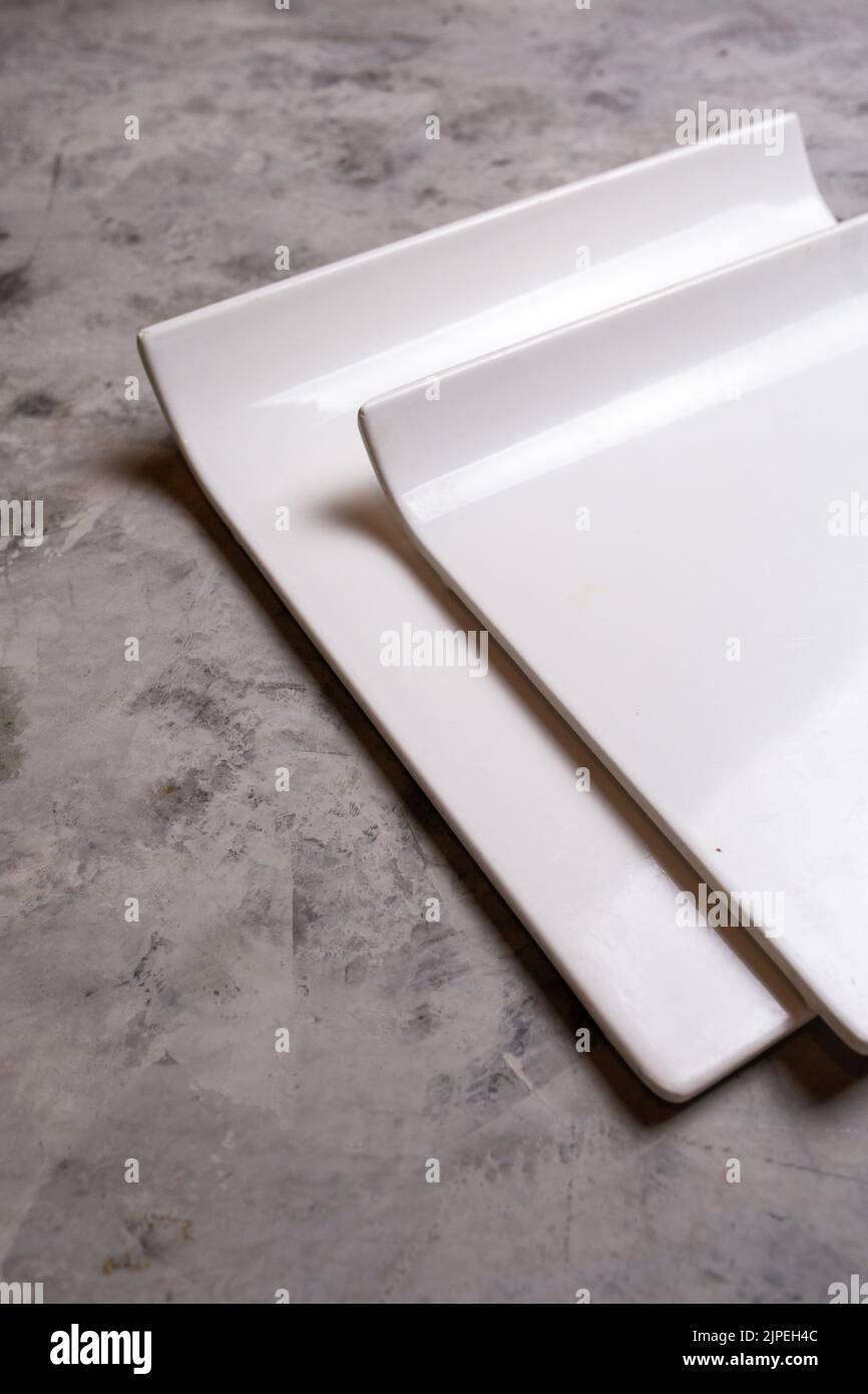 white ceramic square plates on a concrete background Stock Photo Alamy