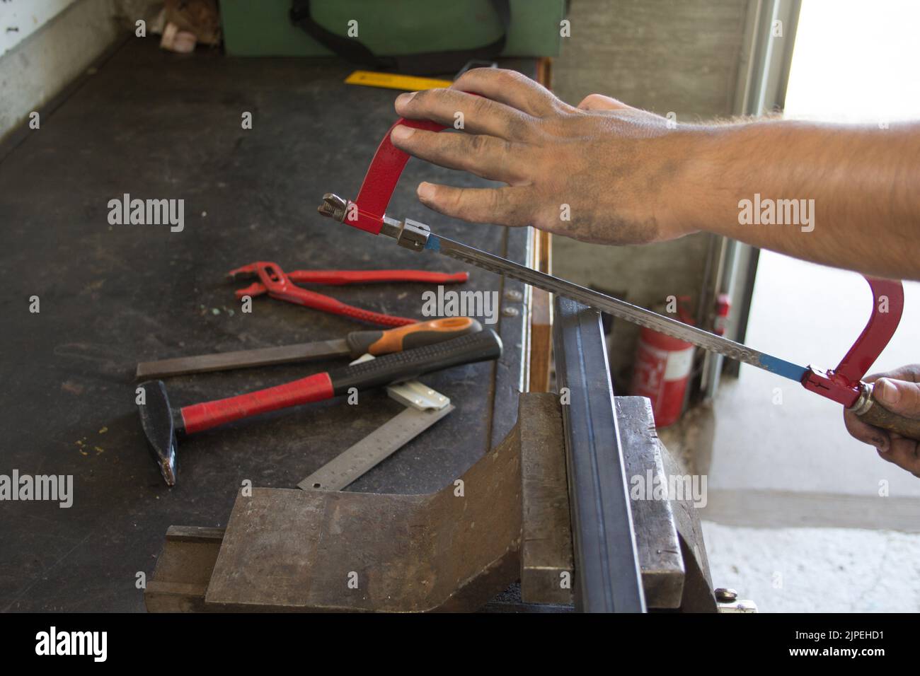 Hands of a blacksmith in his cutting a piece of iron pipe with