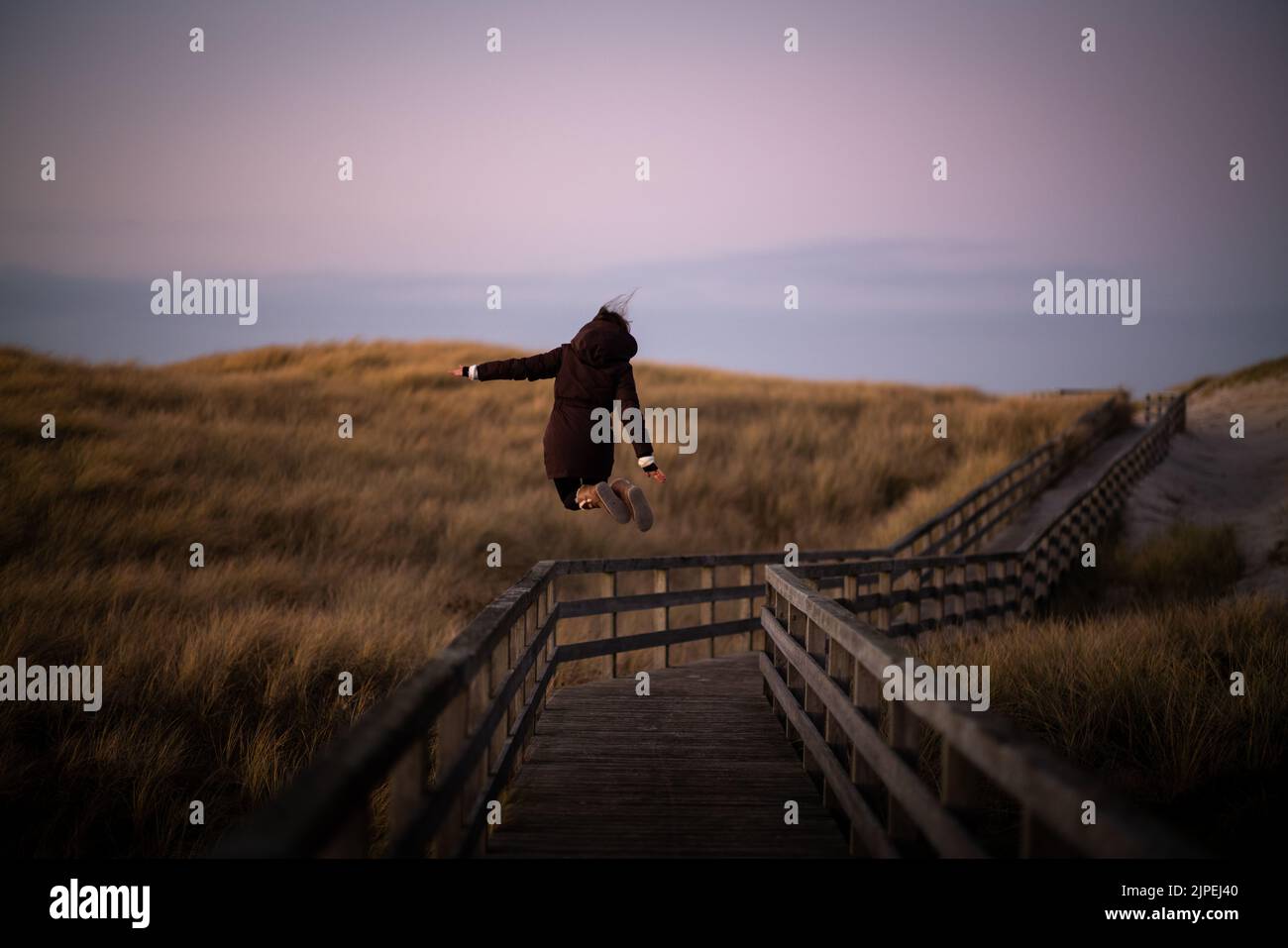 Young woman jumps on boardwalk on Sylt, Germany Stock Photo