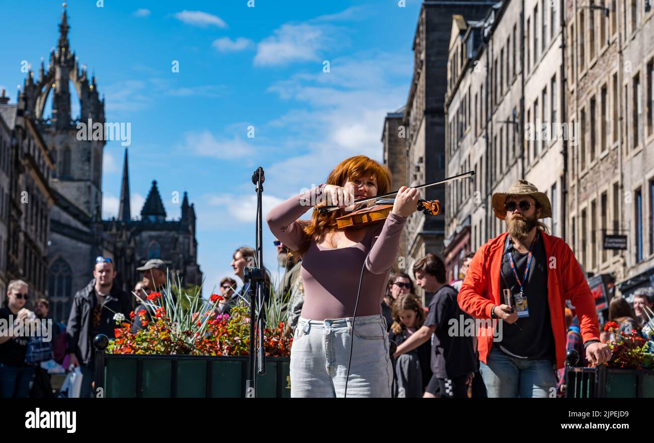 Royal Mile, Edinburgh, Scotland, UK, 17th August 2022. Performers on Royal Mile in the sunshine. Pictured: Credit: Meg Lagrande performing on the street playing the violin or fiddle as people walk past. Sally Anderson/Alamy Live News Stock Photo