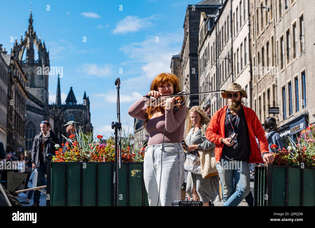 Royal Mile, Edinburgh, Scotland, UK, 17th August 2022. Performers on Royal Mile in the sunshine. Pictured: Credit: Meg Lagrande performing on the street playing the violin or fiddle as people walk past. Sally Anderson/Alamy Live News Stock Photo