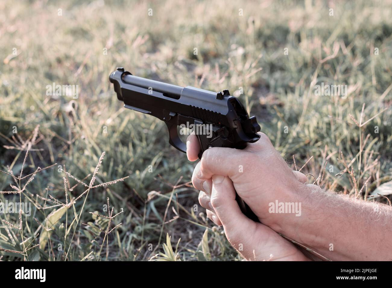 pistol in male hands, fingers pull the trigger. Handling weapons, shooting in the street Stock