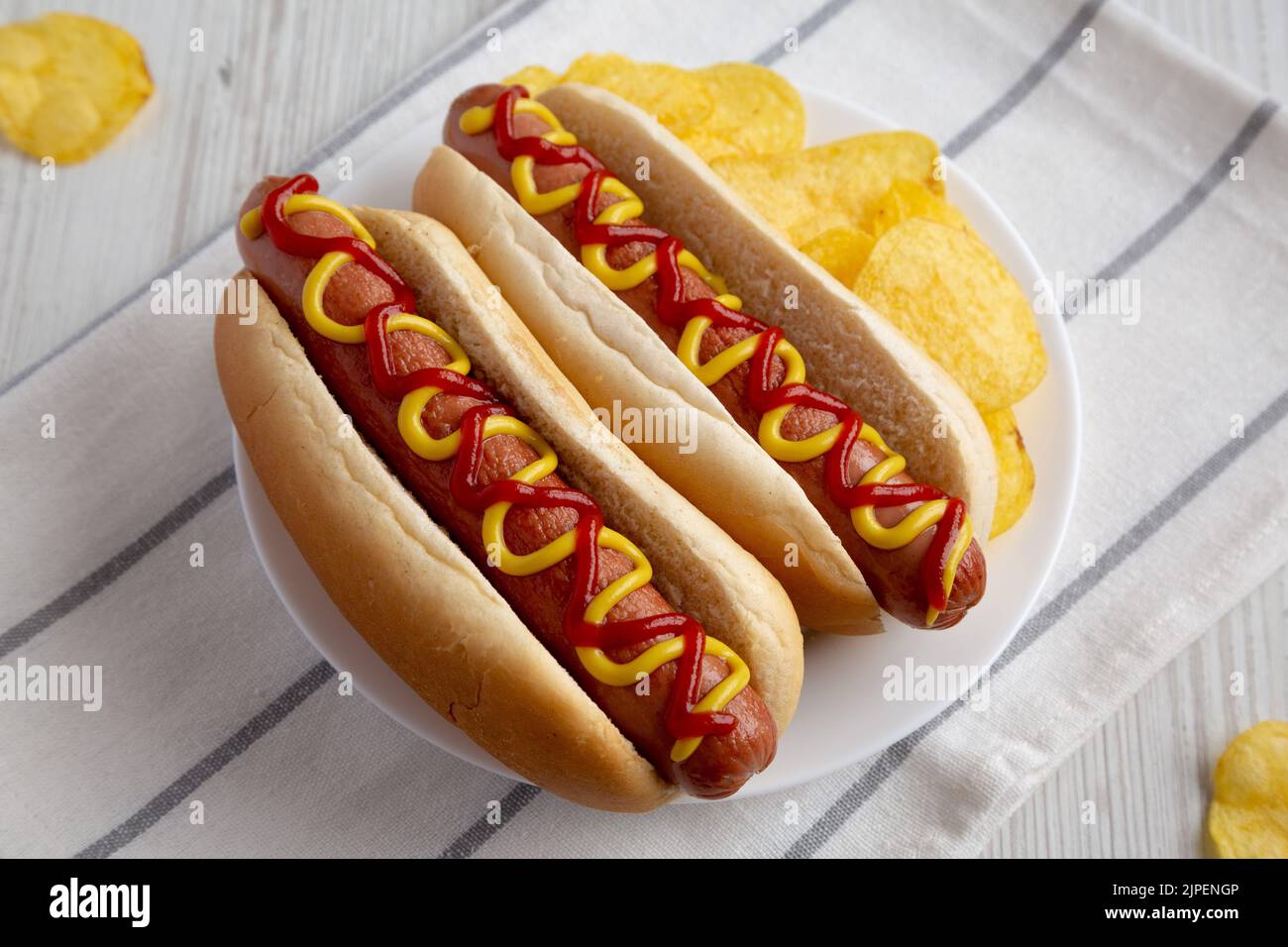 Homemade Hot Dog with Ketchup and Yellow Mustard with Chips on a Plate
