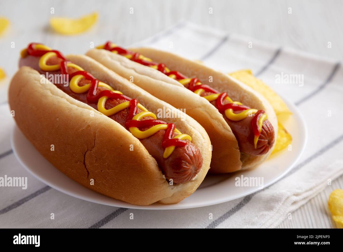 Homemade Hot Dog with Ketchup and Yellow Mustard with Chips on a Plate
