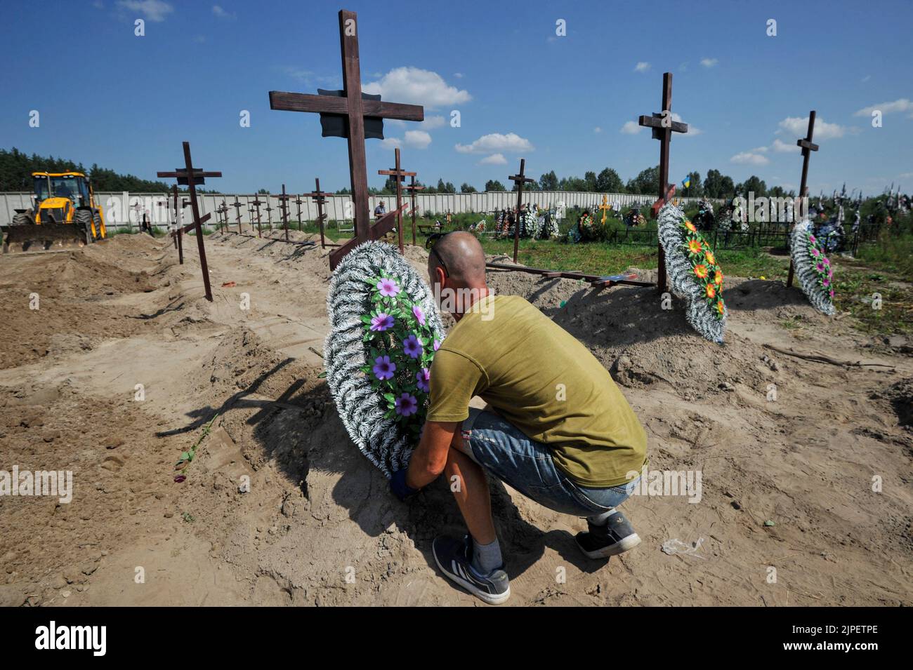A municipal worker sets a wreath on the grave of an unidentified person who was killed by the Russian military during the occupation of the city of Bucha. On Wednesday, 21 unidentified people who were killed by the Russian military in February-March 2022 were buried at the local cemetery. Russia invaded Ukraine on 24 February 2022, triggering the largest military attack in Europe since World War II. Stock Photo