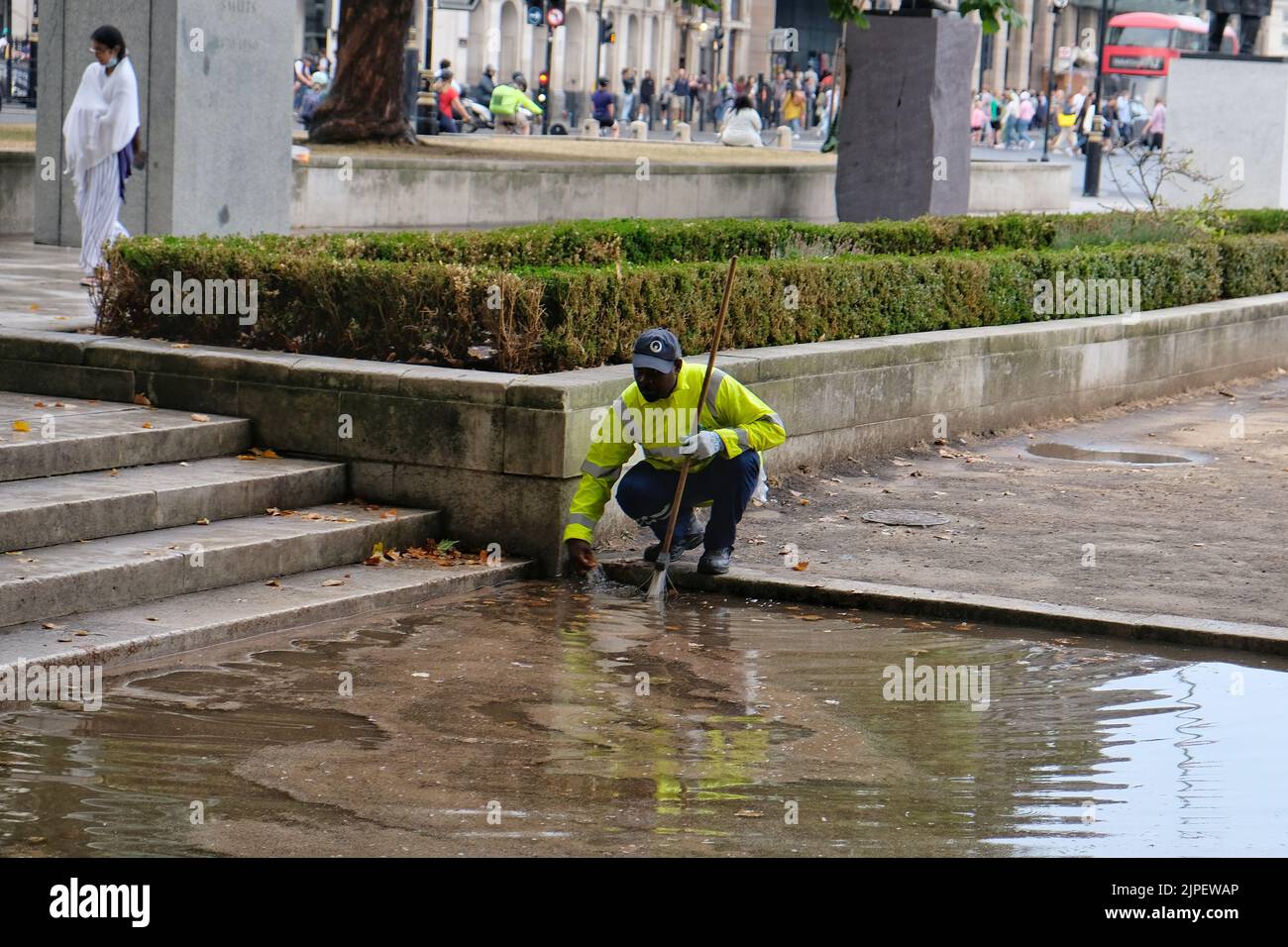 London, UK. 17th August, 2022. A worker in Parliament Square attempts to free drains of debris and leaves after heavy showers hit the capital, causing localised flooding in parts of the city. Credit: Eleventh Hour Photography/Alamy Live News Stock Photo