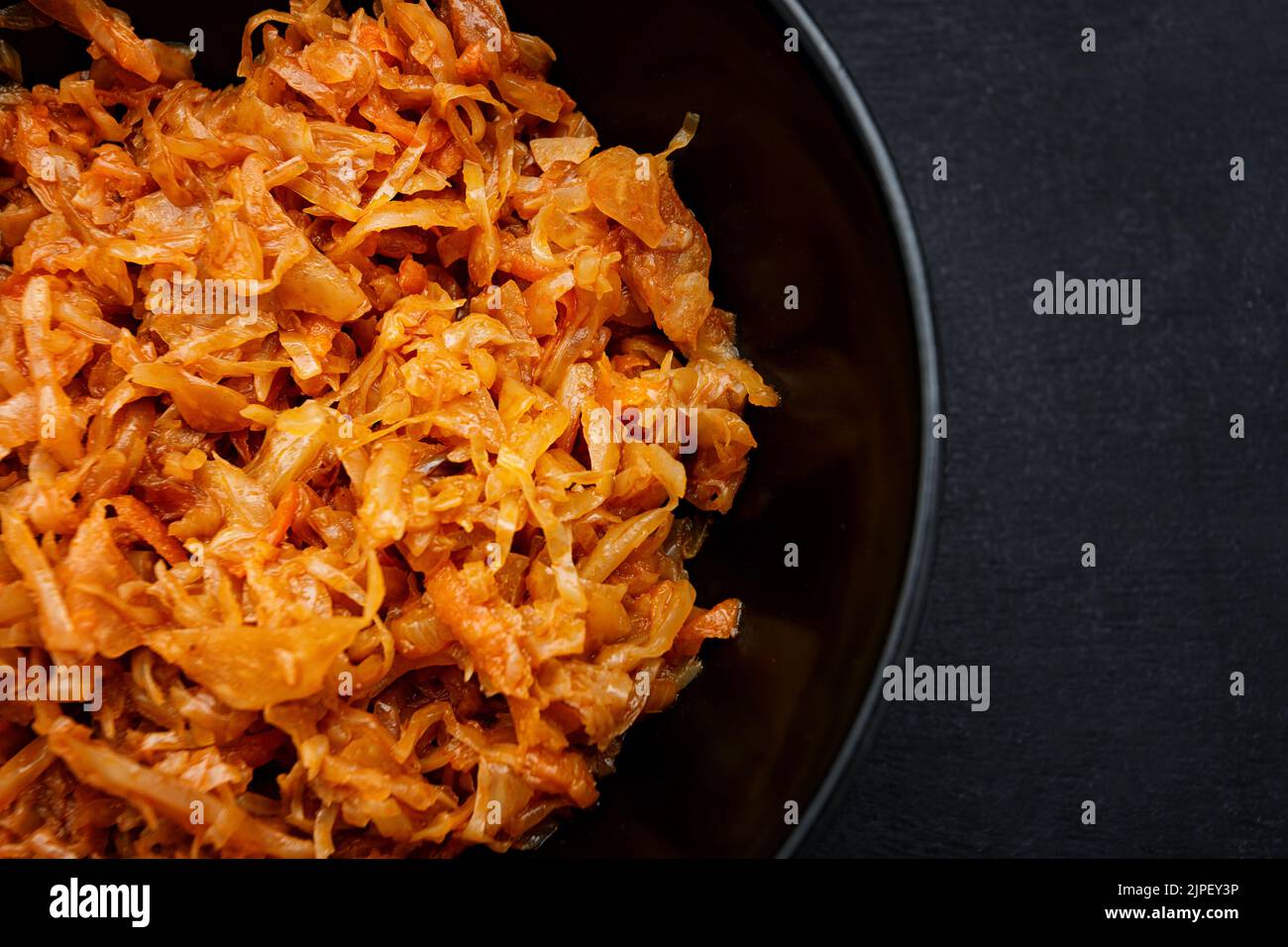 Stewed cabbage in a plate on a dark background close-up Stock Photo