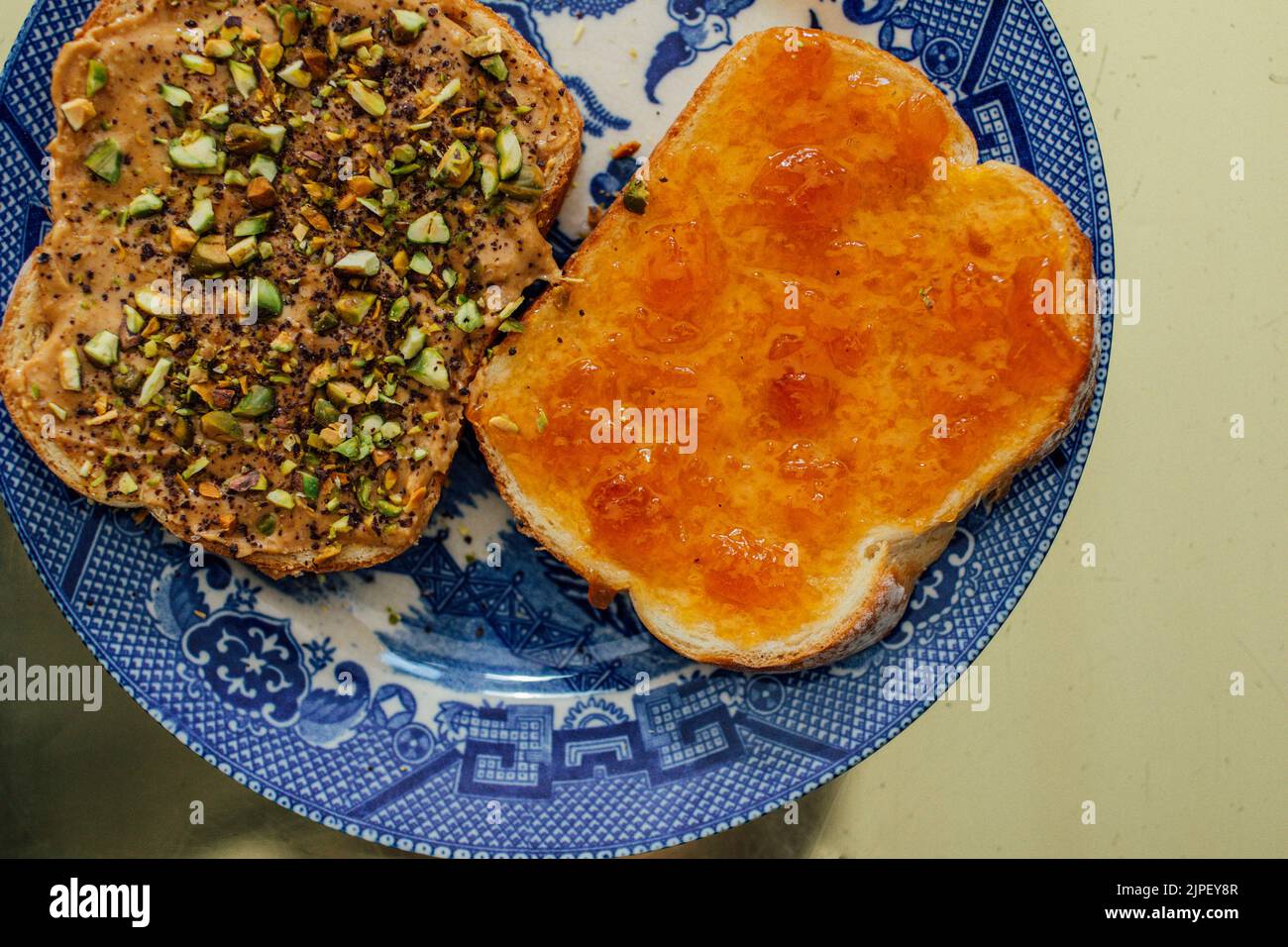 open faced peanut butter and apricot jelly sandwich with pistachios