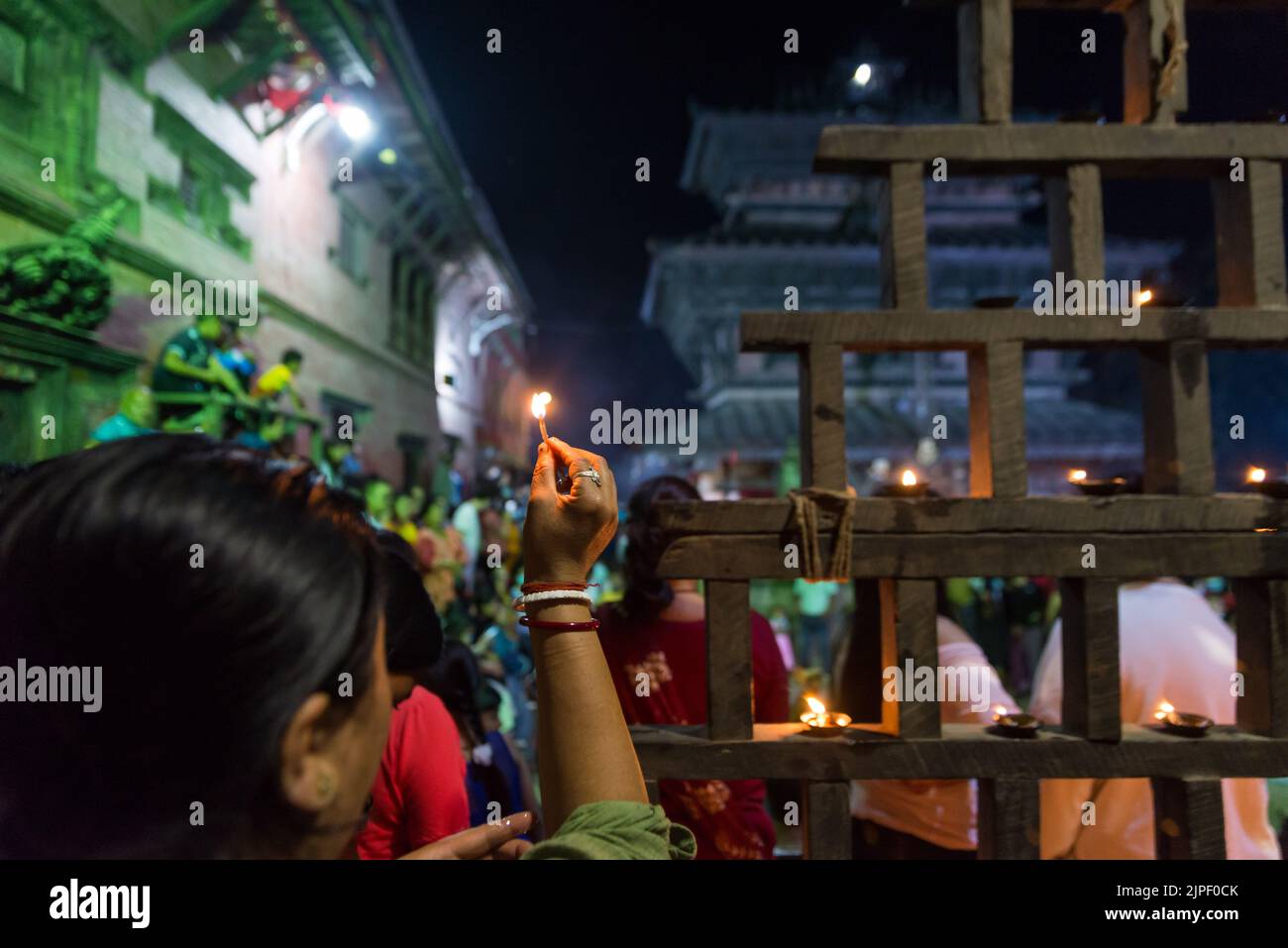A devotee offering an oil lamp during the Bagh Bhairab festival celebration. On the occasion of the Bagh Bhairab festival, devotees circumambulate Bagh Bhairab Temple for 108 times for blessings with success and good health. Stock Photo