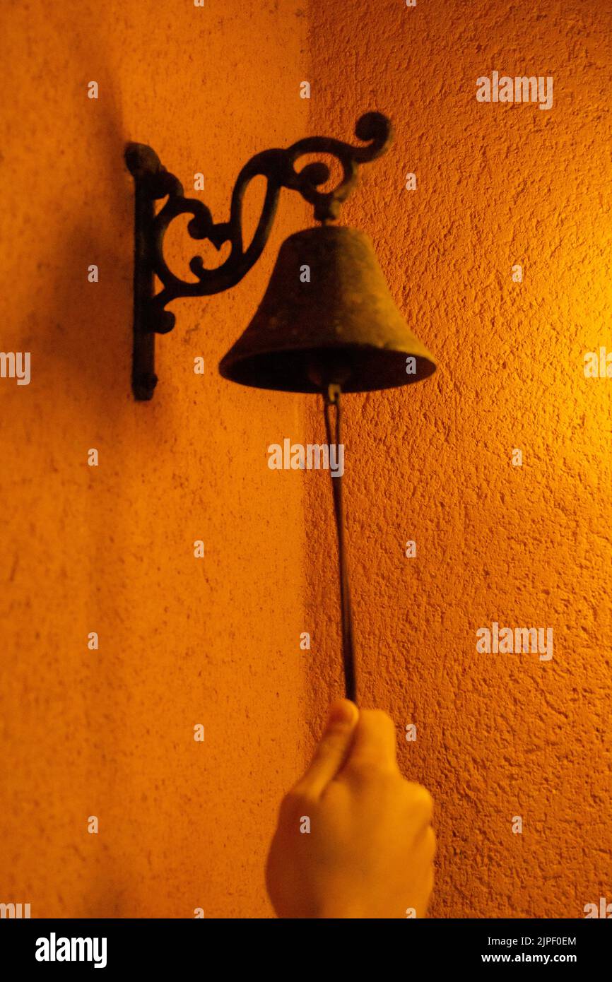 detail of a person ringing a small church bell to be used as a doorbell ...