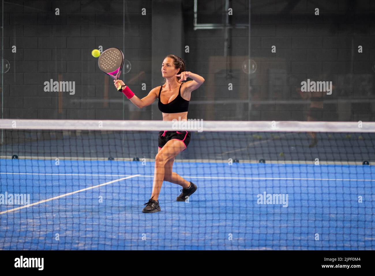Woman playing padel in a blue grass padel court indoor - Young sporty ...