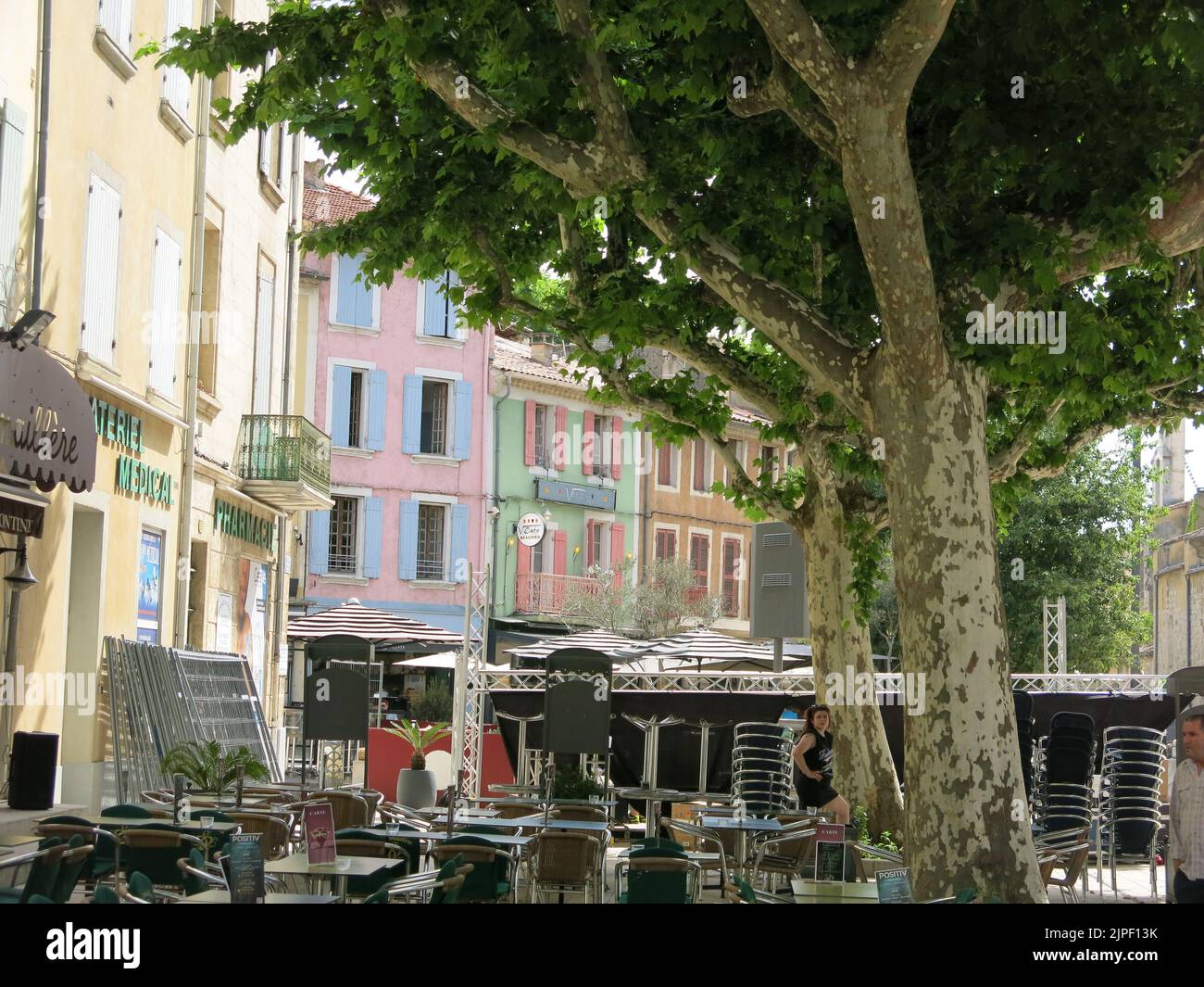 Brightly coloured buildings in the French historic city of Orange with cafes and restaurants in the tree-lined square. Stock Photo
