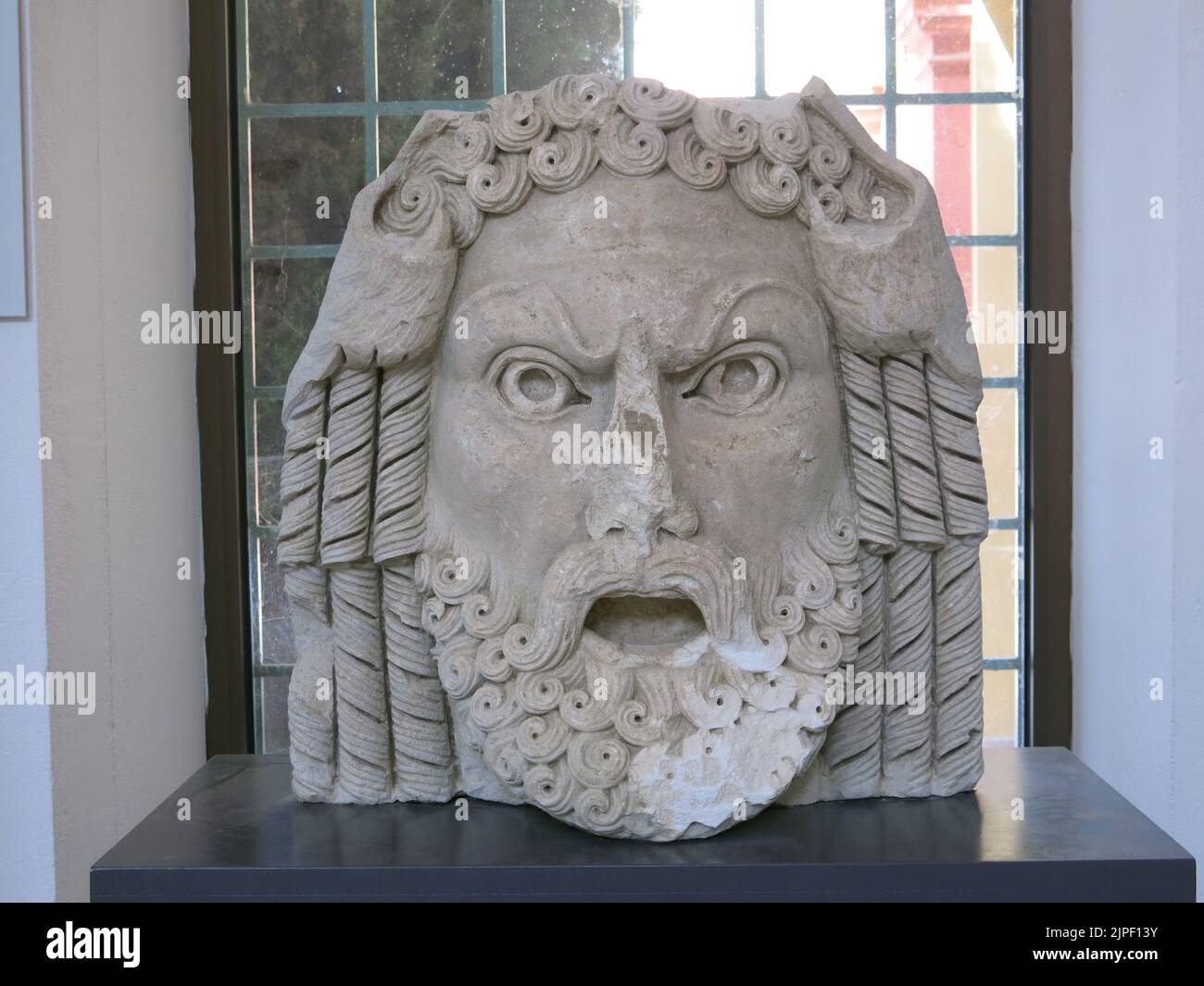 An intricately carved stone mask of the face of Hercules on display with other Roman artefacts at the Museum of Art & History in Orange. Stock Photo