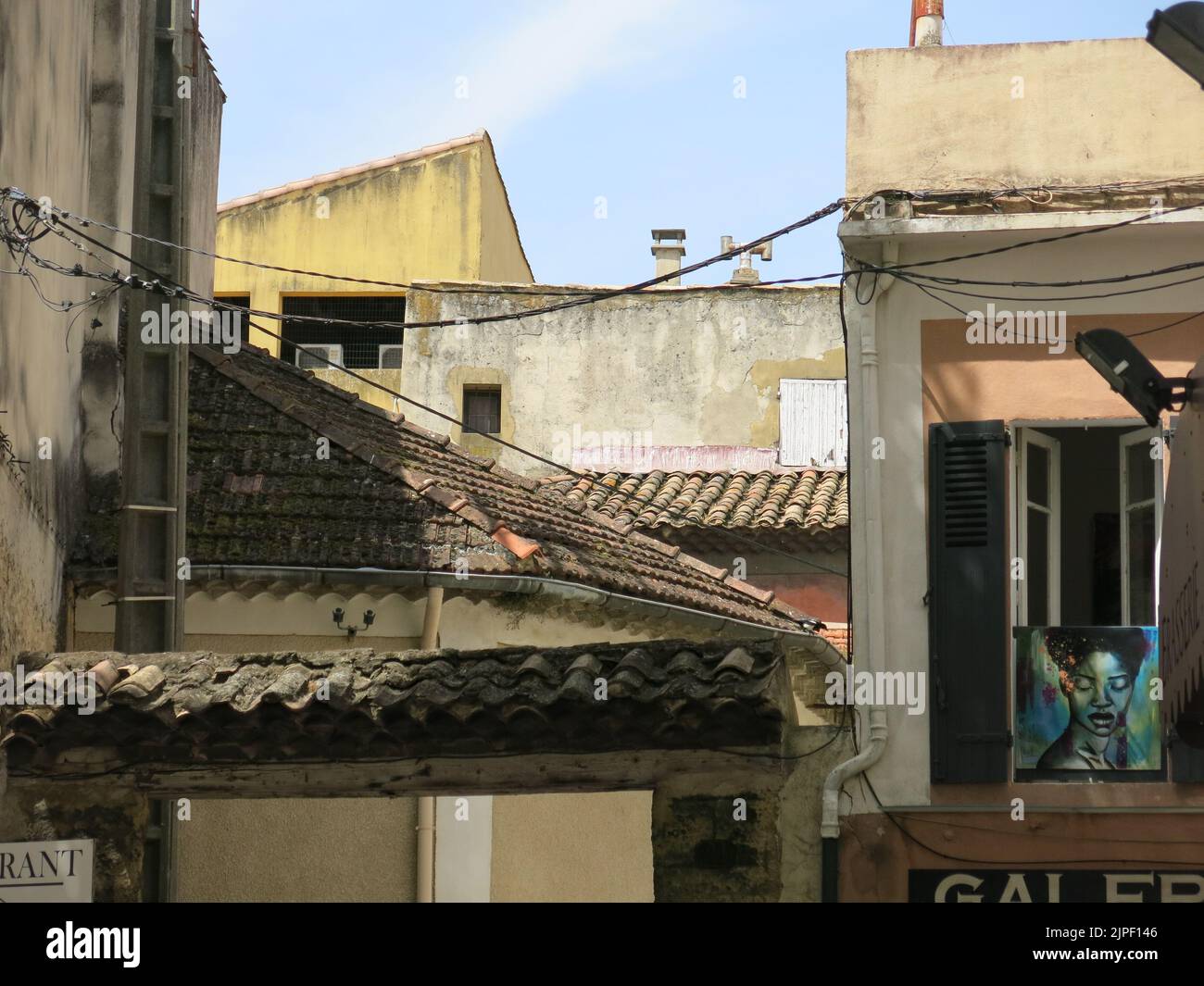 Rooftop scene in the historic city of Orange in southern France with cabling between the buildings and tiled roofs. Stock Photo
