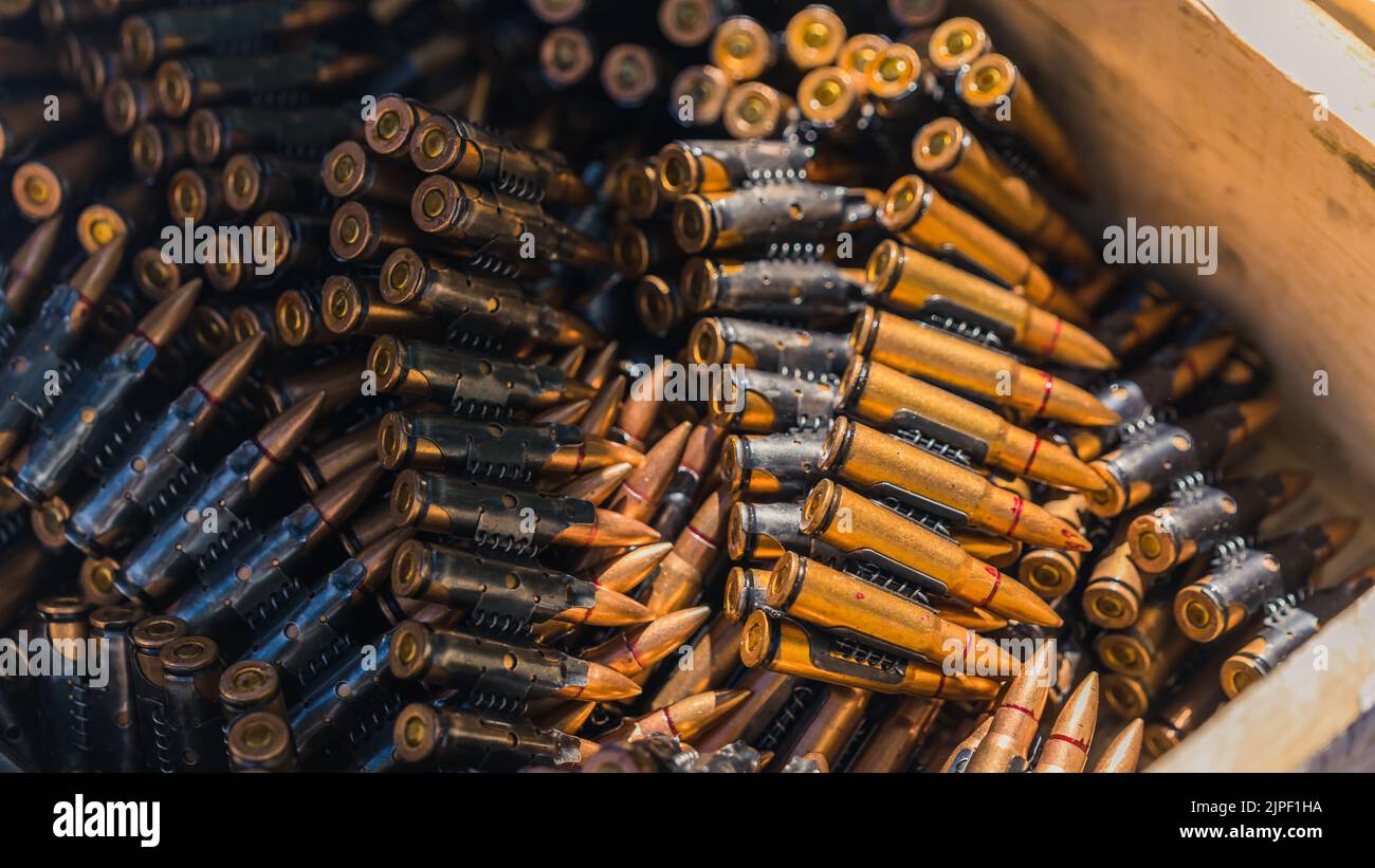 Close-up of golden rifle bullet tapes for machinegun stored in wooden chest. Military equipment. Ammunition. Horizontal shot. High quality photo Stock Photo
