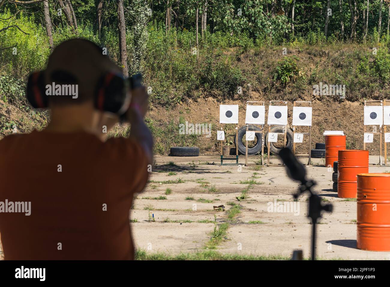 Rear view of man in safety headphones next to field glass practicing