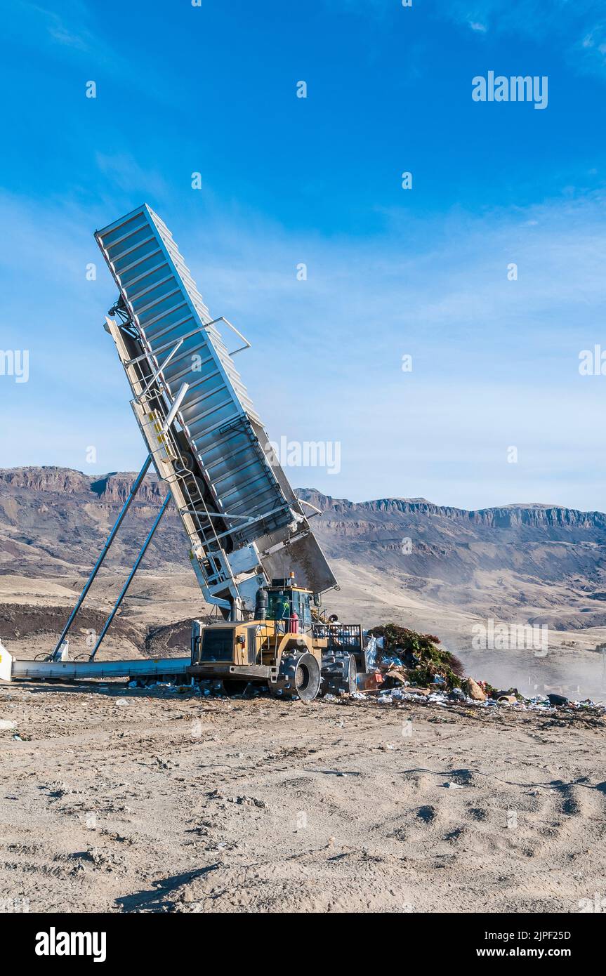 Landfill tipper lifts trailer container to a high angle to dump all the ...