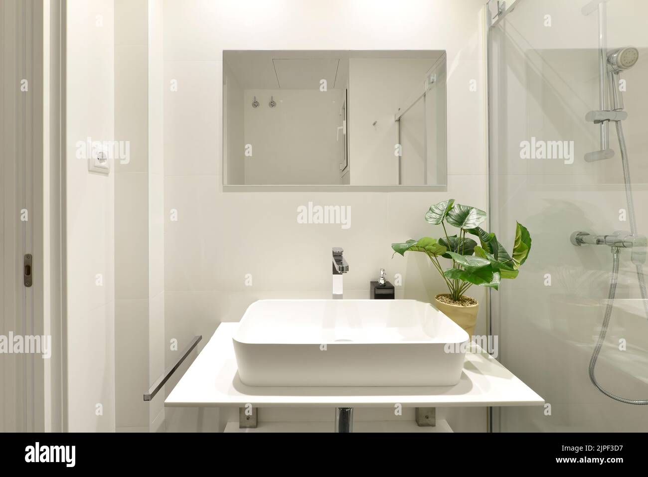 Plain white tiled bathroom with rollin glass shower stall, designer