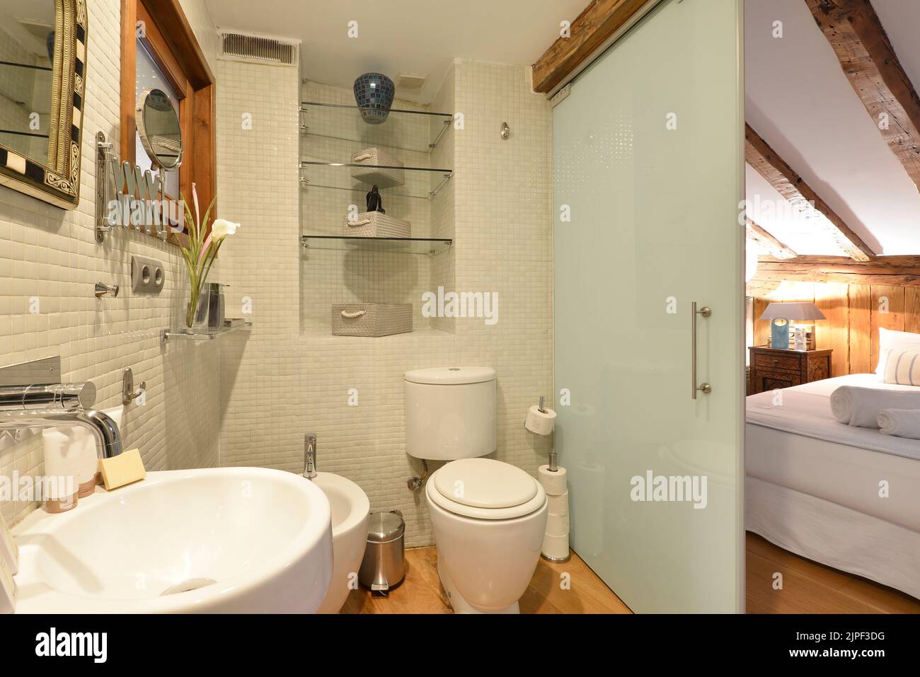 En-suite bathroom with tiled tiles, translucent glass sliding door and white porcelain design toilets Stock Photo