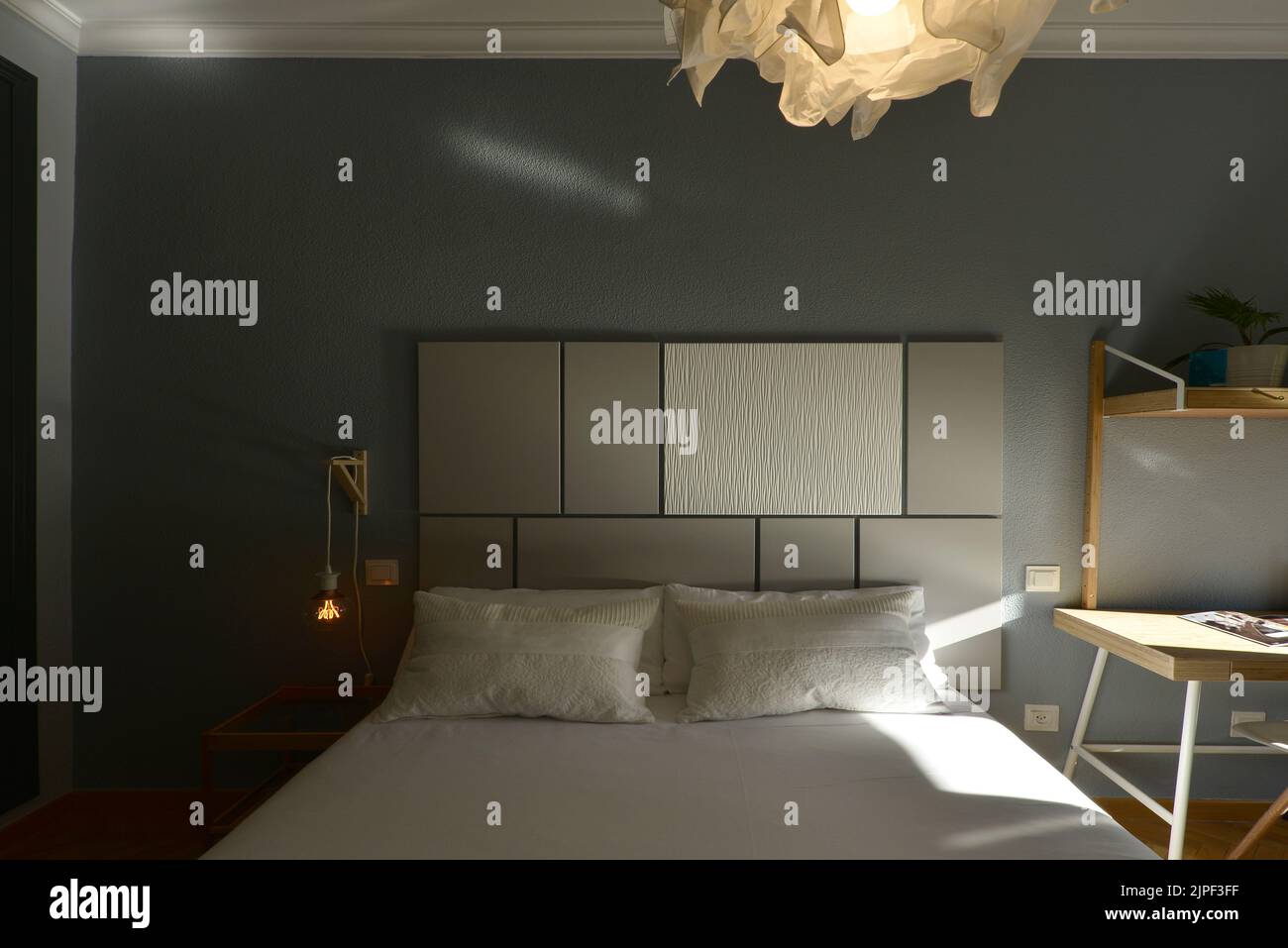 Bedroom decorated in industrial design with wooden headboard, lamps