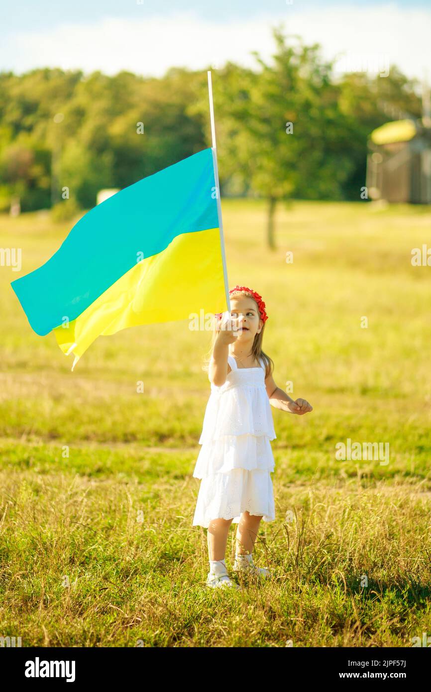 The flag of Ukraine is developing in the hands of a Ukrainian girl. Preschooler walks in Pirogovo on Ukraine's Independence Day and Flag Day Stock Photo