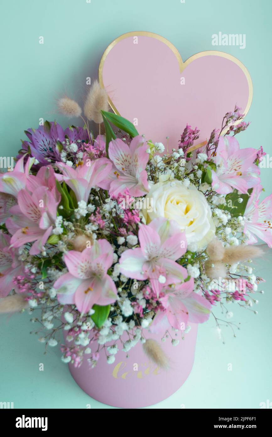 Delicate bouquet pink lilies, white roses, gypsophila. Turquoise background. Pink Heart, copy