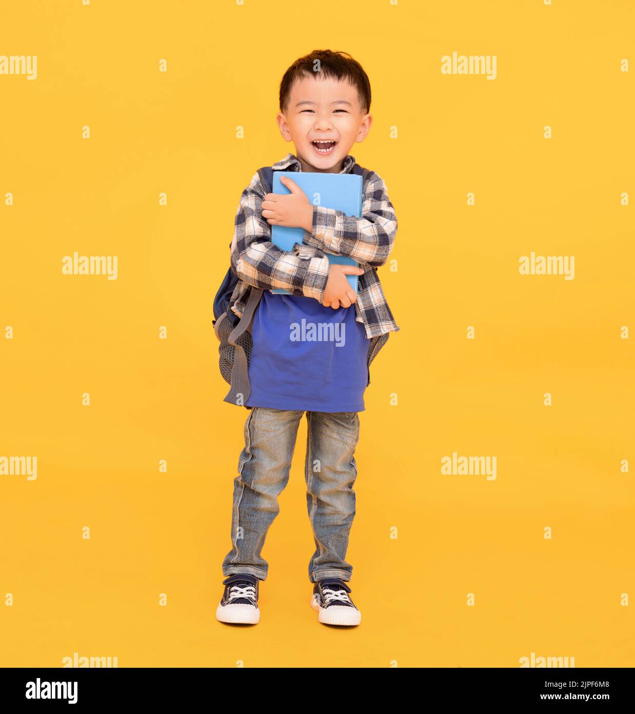 happy asian kid holding or hugging  big book over yellow background Stock Photo