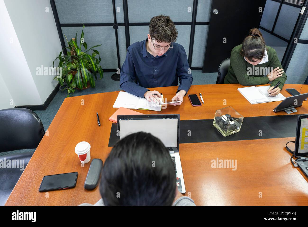 Group of employees sitting around the office meeting table working on ...