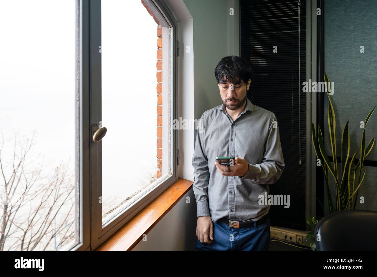 Latino businessman working in an office overlooking the river using the phone. Stock Photo